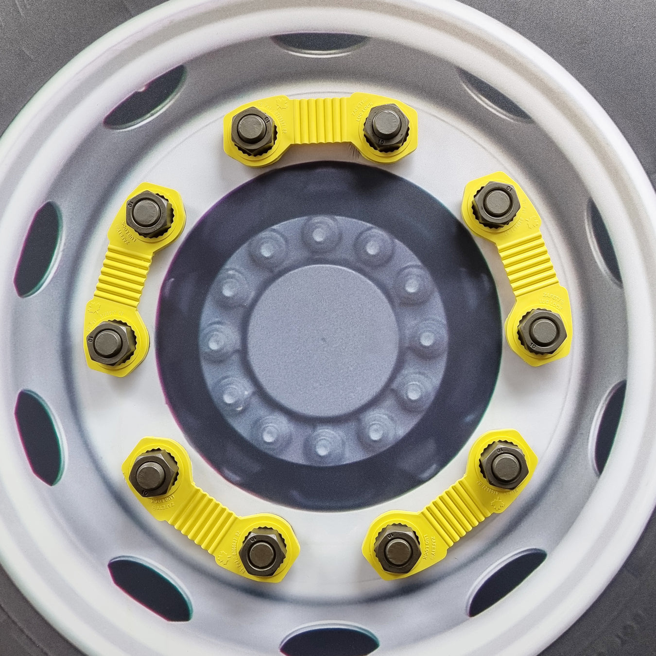 The Zafety Lug Lock device fits snugly over two adjacent nuts on the truck or bus wheel to secure them together. The wheel has 5 zafety devices across a total of 10 wheel nuts.