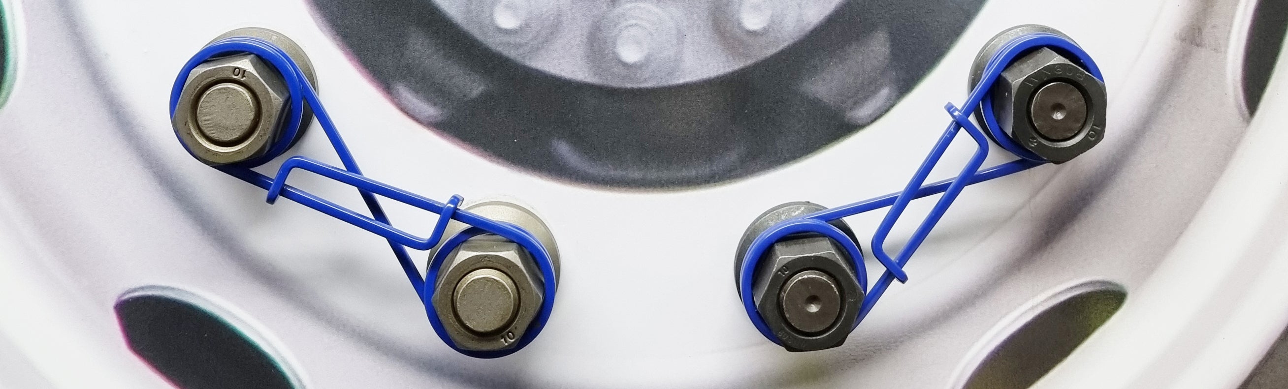 Close up image of yellow Zafety products attached to a lorry wheel. This is to the left of the frame, with the right having slightly out of focus white lorry cabs, allowing you to know it's for trucks but keeping the focus on the wheel devices.