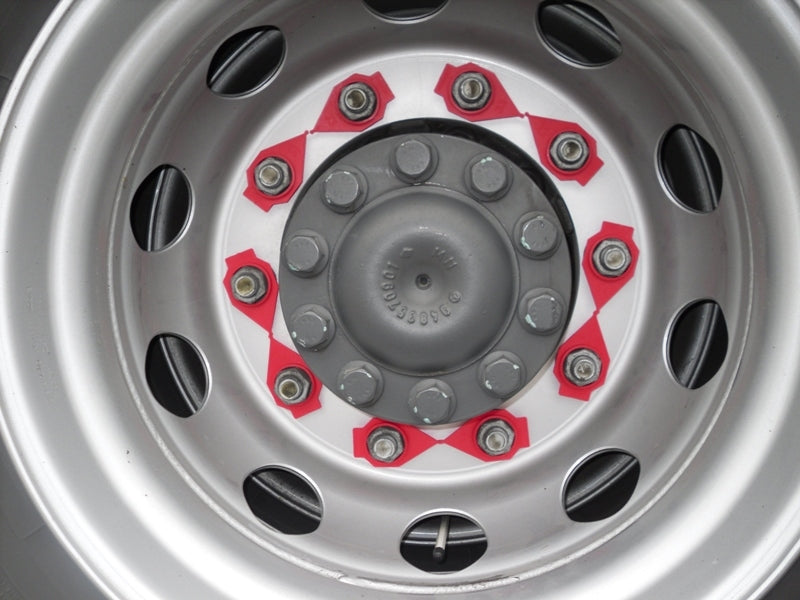 Close up image of yellow Zafety products attached to a lorry wheel. This is to the left of the frame, with the right having slightly out of focus white lorry cabs, allowing you to know it's for trucks but keeping the focus on the wheel devices.