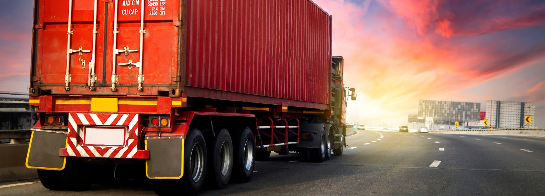 Heavy goods vehicle (HGV) logistics and freight transport on an open road with a dramatic sky.