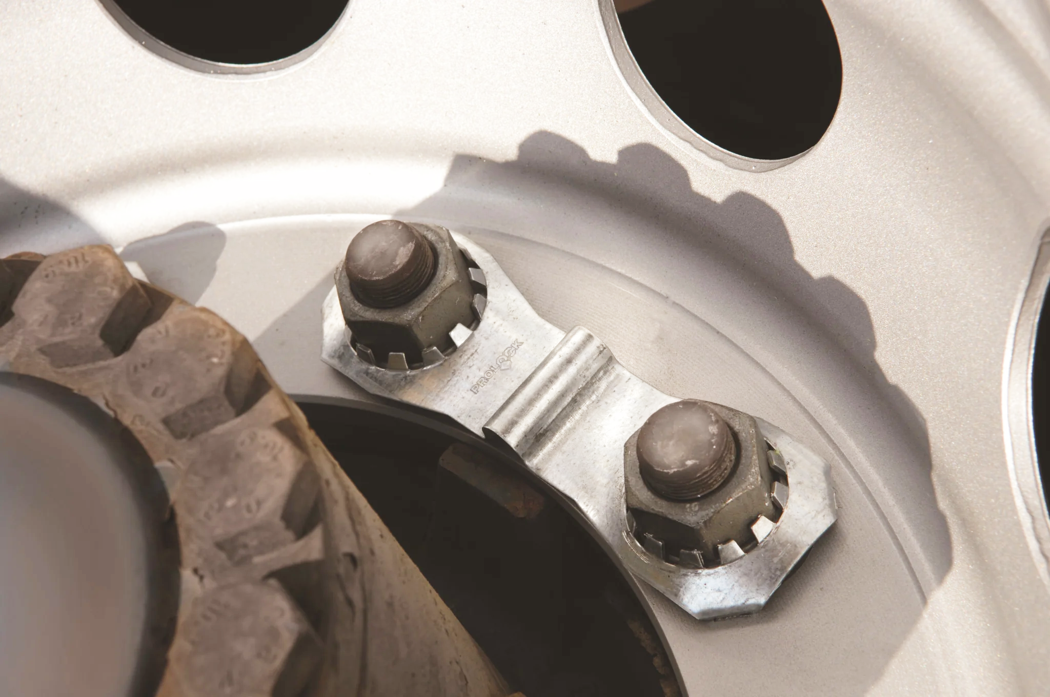 a closeup of a pro lock attached to a wheel, demonstrating how it fits. It's snug, secure and looks good in a silver metallic that matches the wheel.