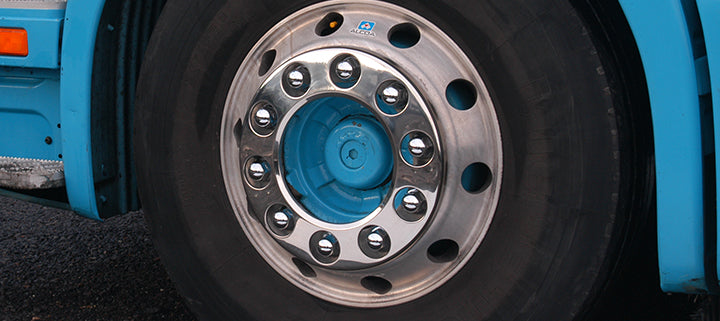 Stainless steel nut ring fitted to a blue vehicle. A close up of the wheel shows the nut ring attached, creating a clean and sleek look. The nut ring is shinier and more reflective than the wheel behind it, showing the difference it can make. The wheel nuts slightly poke through the holes of the ring.