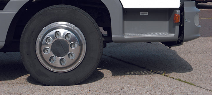A close up of the vinci style trims on a vehicle. You can see the wheel nuts through the holes that surround the centre. The wheel looks smart and put together. It looks to be a sunny day with harsh shadows and bright colours.